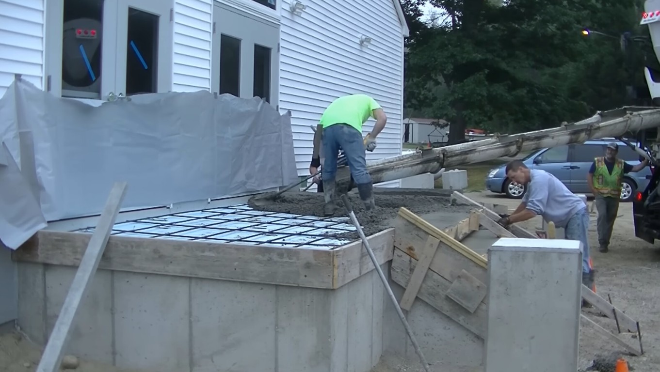 Concrete slab foundation being poured and formed at a construction site