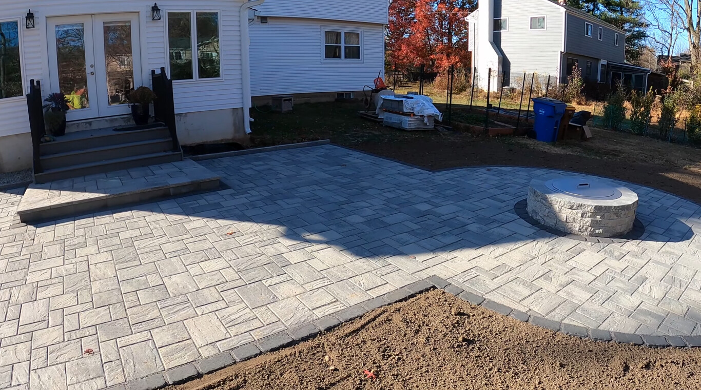 Stamped concrete patio with fire pit area and steps at a residential backyard